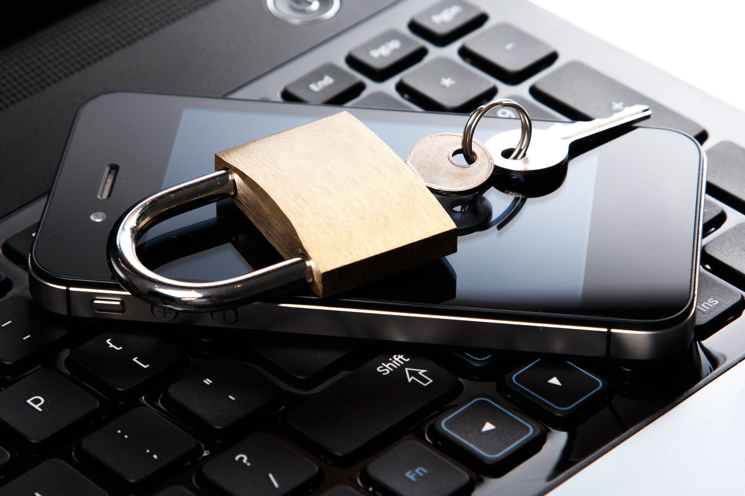 A smartphone with a padlock and keys placed on top of a laptop keyboard, symbolizing data security, device protection, and digital privacy.