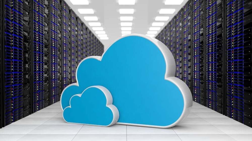 Two large blue cloud icons placed in the middle of a modern server room; representing cloud computing, data storage, and network infrastructure.