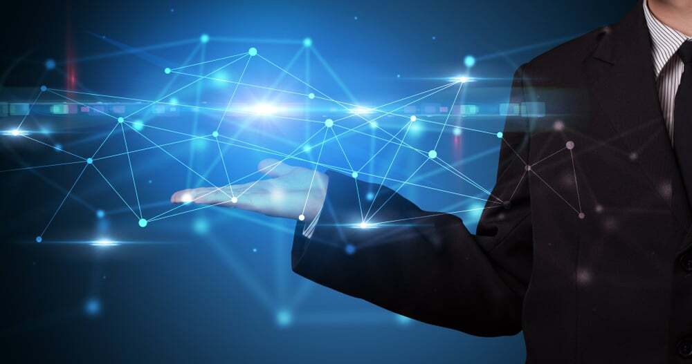 A person in a suit holding a digital network of connected glowing nodes and lines, symbolizing data connectivity, innovation, and modern technology integration.