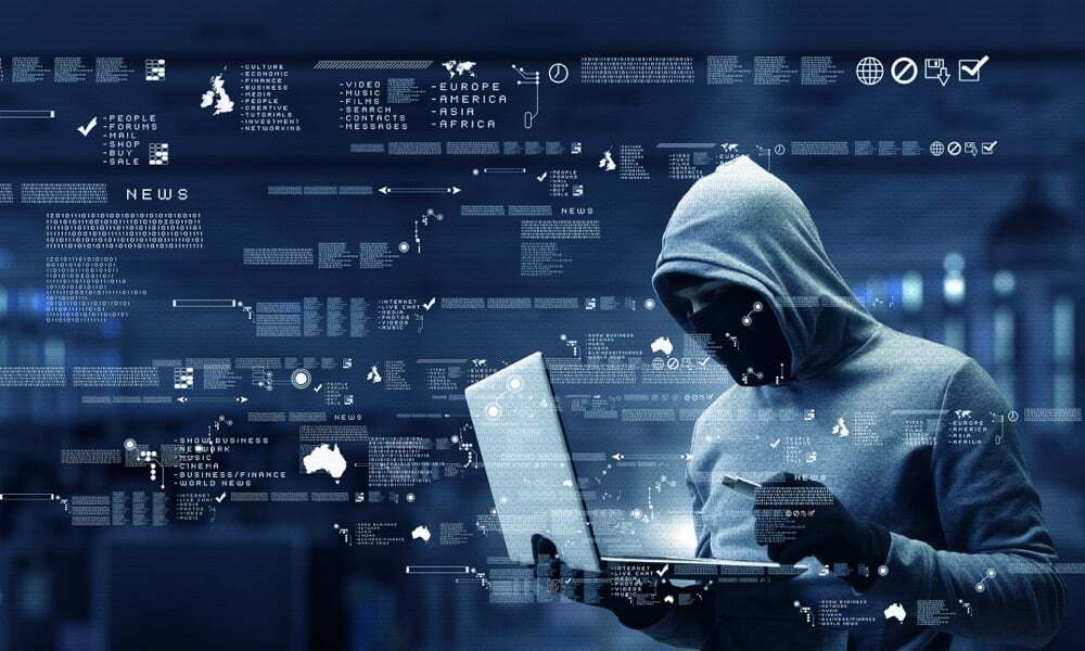 A person in a hooded sweatshirt using a laptop while holding a credit card, surrounded by floating digital data and world maps; representing cybercrime, hacking, or online identity theft.