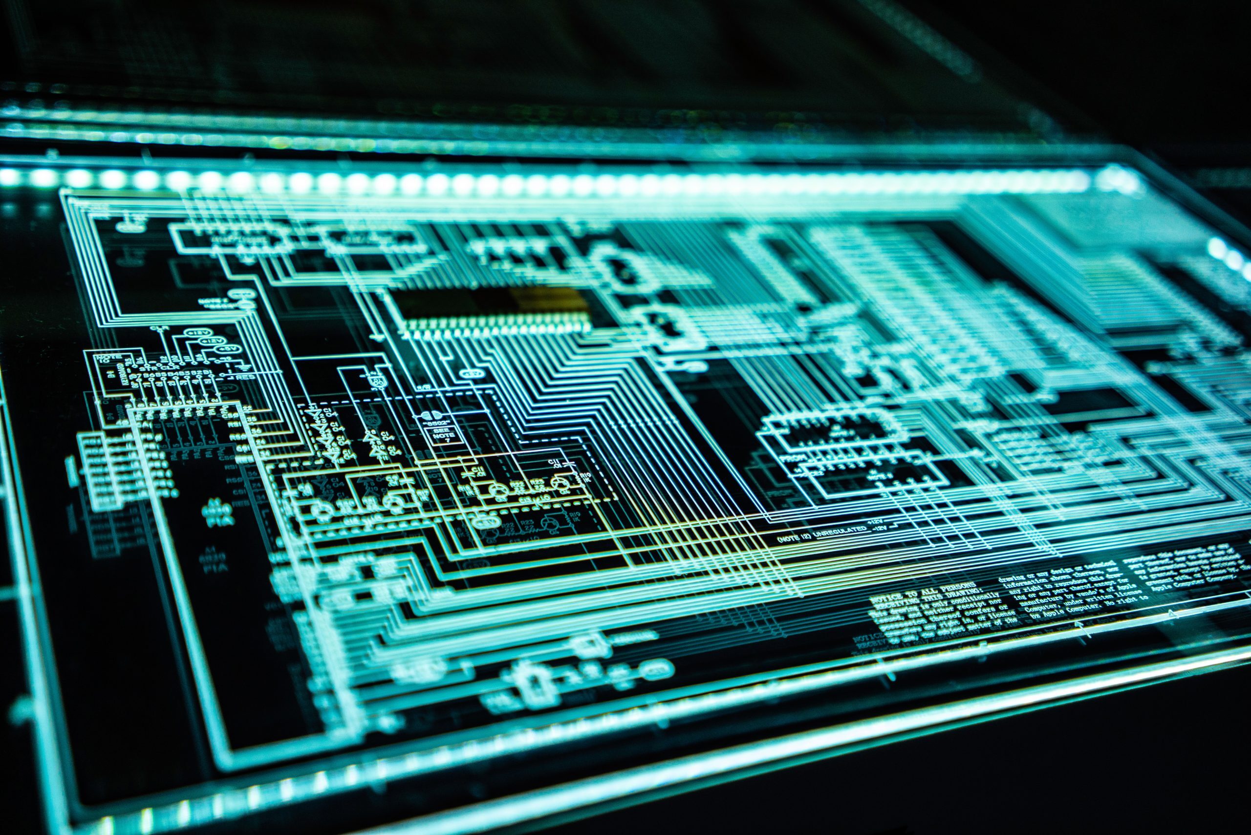 A close-up view of a digital circuit board glowing with blue and green light, symbolizing advanced technology, data processing, and electronic systems.